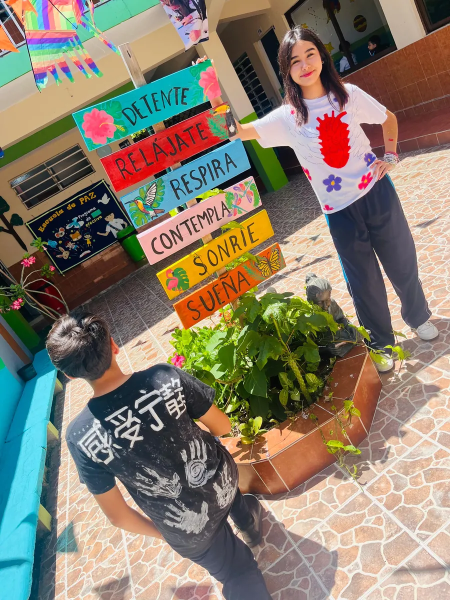 Estudiantes de Colegio Latino participando en una actividad del Programa de Paz, junto a un letrero con mensajes de bienestar emocional