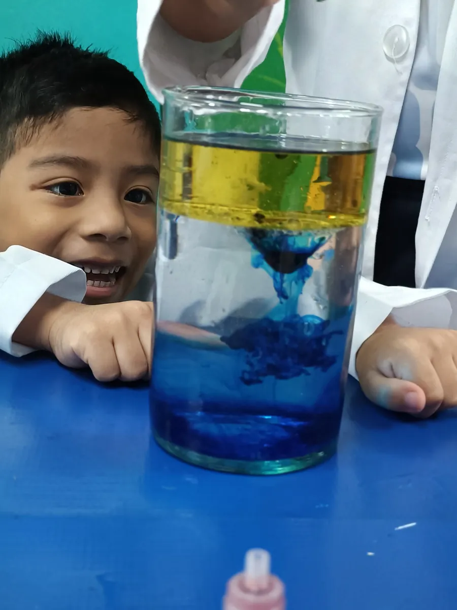Estudiante de Preescolar de Colegio Latino observando un experimento de mezcla de líquidos de colores en el Science Club