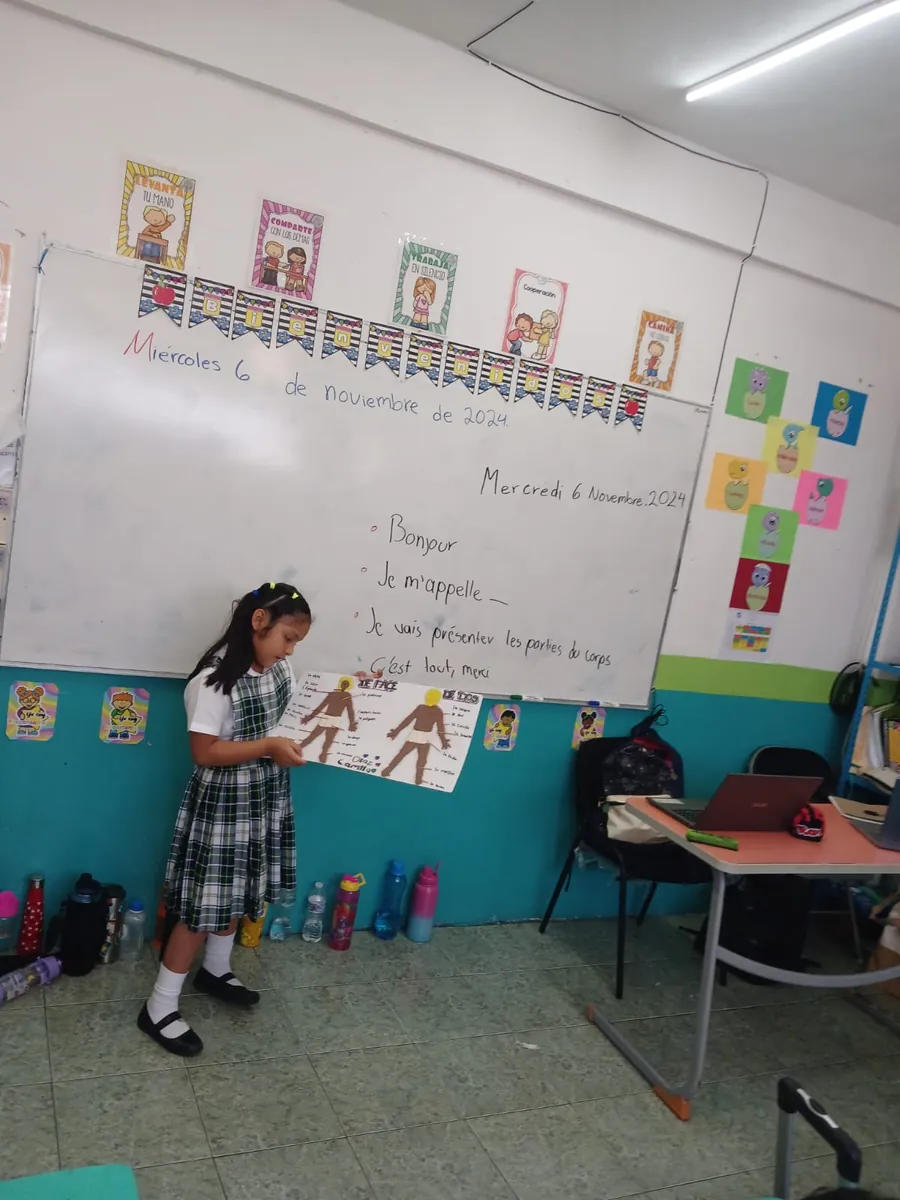 Estudiante de Primaria de Colegio Latino presentando una actividad de francés frente al pizarrón