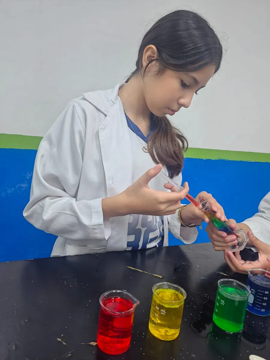 Estudiante de Secundaria de Colegio Latino realizando un experimento con líquidos de colores en el laboratorio
