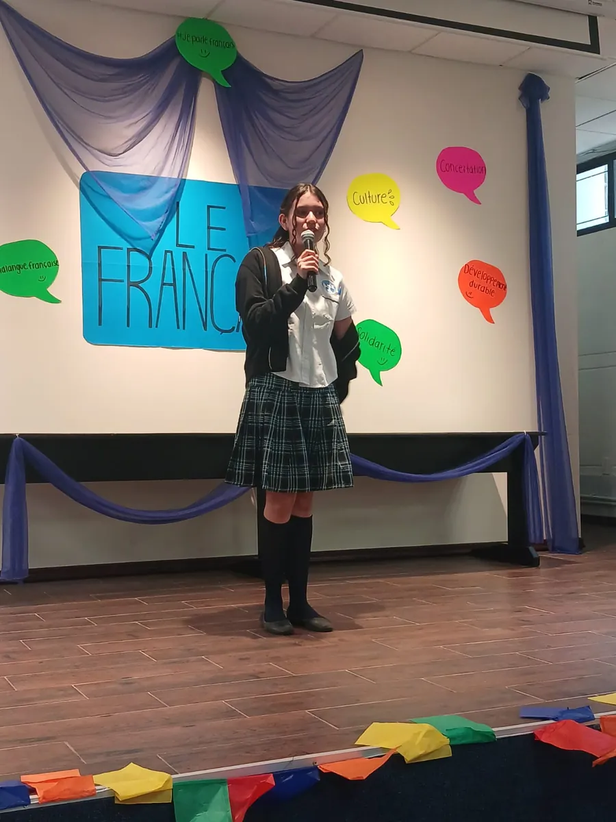 Estudiante de Secundaria de Colegio Latino presentando frente a un mural con vocabulario en francés