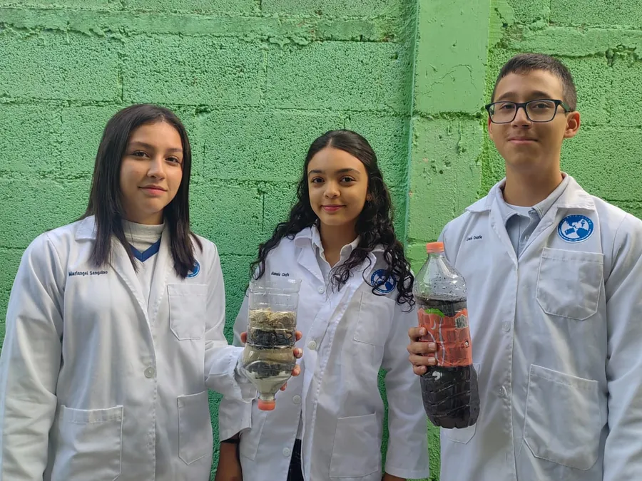 Estudiantes de Secundaria de Colegio Latino presentando un proyecto de ciencias con muestras experimentales