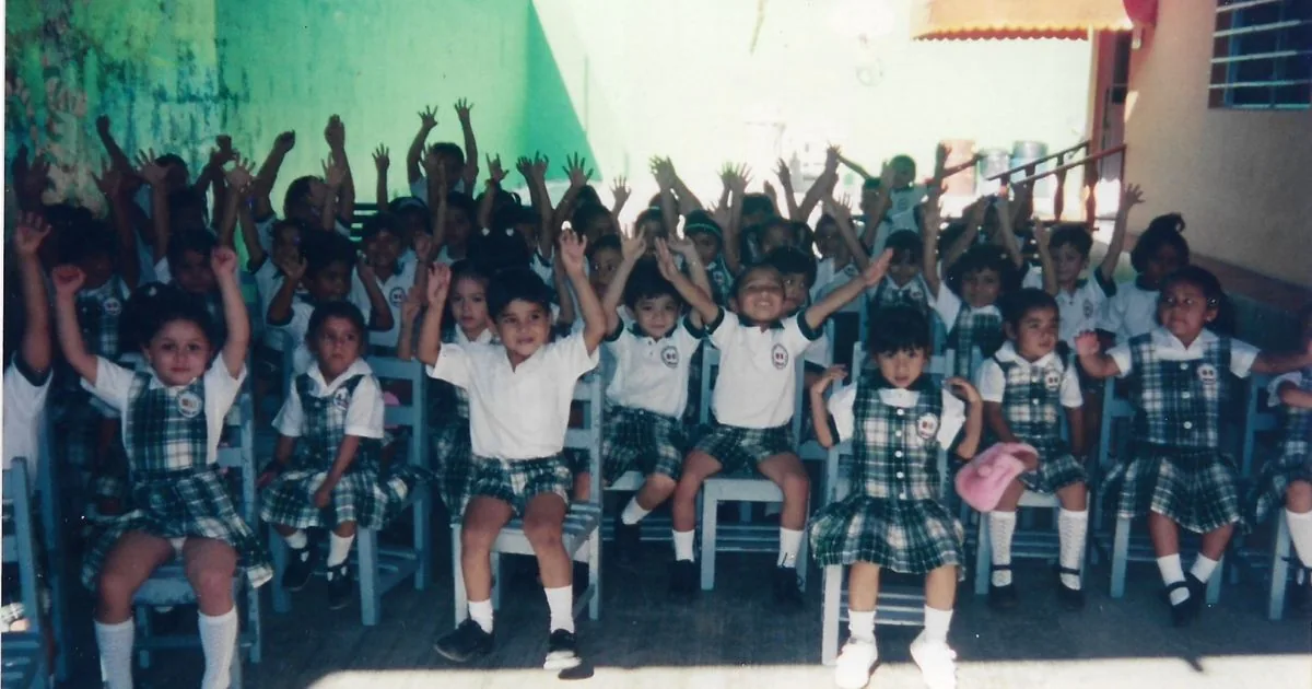 Generación de alumnas y alumnos de Colegio Latino con las manos levantadas en una actividad escolar